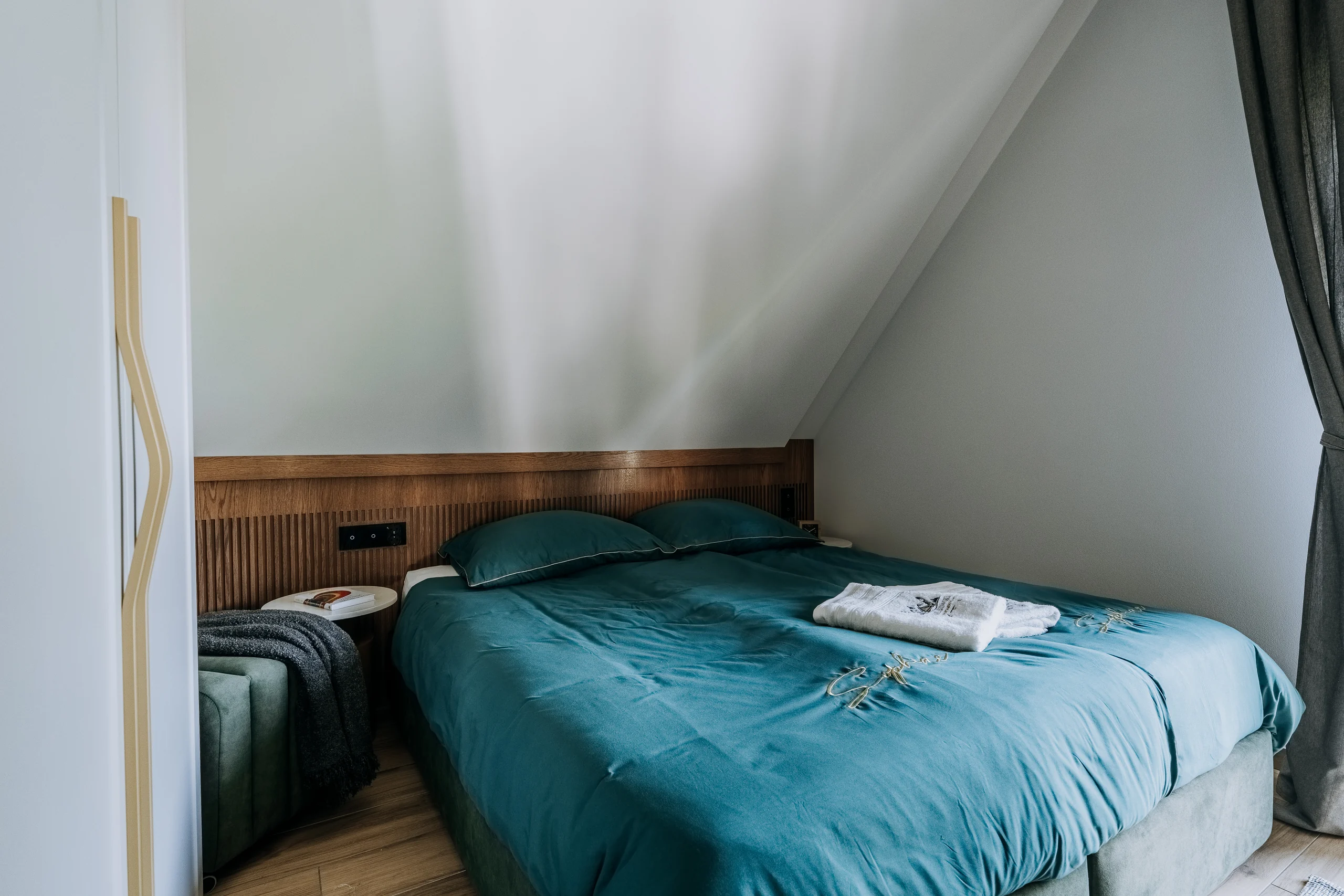 Podwójne łóżko pod skosem w sypialni apartamentu New York